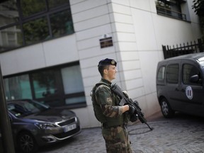 French soldier stands near the scene where French soldiers were hit and injured by a vehicle in the western Paris suburb of Levallois-Perret near Paris, France, Wednesday, Aug. 9, 2017. French police are searching for a driver who slammed his BMW into a group of soldiers, injuring six of them in an apparent ambush before speeding away, officials said. The incident in Levallois, northwest of Paris, is the latest of several attacks targeting security forces in France.(AP Photo/Kamil Zihnioglu)
