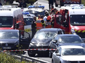 French security forces and emergency vehicles surround a car, centre, on a highway between Boulogne-sur-Mer and Calais in northern France that authorities say was used in an attack on soldiers near Paris on Wednesday, Aug. 9, 2017.