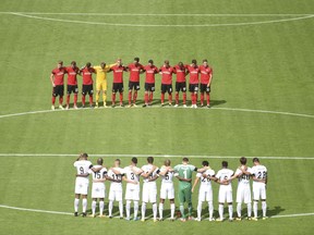 The two teams stand for a minute of silence in memory of those killed in the recent terror attack in Barcelona ahead of the German Bundesliga soccer match between SC Freiburg and Eintracht Frankfurt in the Black Forest Stadium in Freiburg, Germany, Sunday, Aug. 20, 2017.  (Patrick Seeger/dpa via AP)