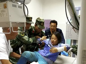 Rescue workers assist an injured woman onto a hospital bed in the aftermath of an earthquake in Jiuzhaigou county in southwestern China's Sichuan province Wednesday Aug. 09, 2017. A strong earthquake shook a mountainous region in southwestern China near a famous national park, killing people and knocking out power and phone networks. (Chinatopix Via AP)