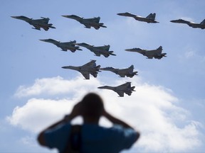 FILE - In this file photo taken on Saturday, Aug. 12, 2017 a man watches Russian military jets performing in Alabino, outside Moscow, Russia. The Russian military says major war games, the Zapad (West) 2017 maneuvers, set for next month will not threaten anyone. (AP Photo/Pavel Golovkin, File)