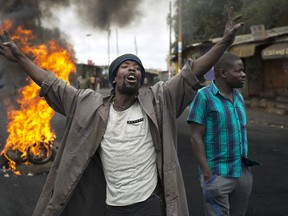 A Kenyan demonstrator reacts to cameras in front of burning tires in Nairobi's Kibera slum Monday, Aug. 14, 2017. Kenyan opposition leader Raila Odinga urged his supporters to skip work on Monday to protest what he charged were rigged elections that gave victory to President Uhuru Kenyatta. The government denounced violent demonstrations as unlawful and urged Kenyans to return to their jobs. (AP Photo/Jerome Delay)