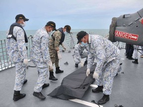 In this photo released by the Royal Malaysian Navy, navy sailors cover an unidentified body on to the deck of KD Lekiu frigate after it was recovered in the waters off the Johor coast of Malaysia, Tuesday, Aug. 22, 2017. The commander of the U.S. Pacific Fleet said some remains of Navy sailors were found in a compartment of the USS John McCain on Tuesday, a day after the warship's collision with an oil tanker in Southeast Asian waters left 10 sailors missing. (Royal Malaysian Navy via AP)