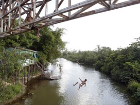 In this Sept. 22, 2011 file photo, a youth jumps from an overpass into a river in Paragominas, northern state of Para, Brazil. Brazil's government revised a decree that strips protection from a national reserve between the northern states of Para and Amapa. The new decree announced late Monday, Aug. 28, 2017, still lifts the reserve designation from a gold- and copper-rich area in the two northern Brazilian states. But President Michel Temer's administration clarifies that mining will not be allowed in conservation or indigenous areas within the former reserve. (AP Photo/Andre Penner, File)