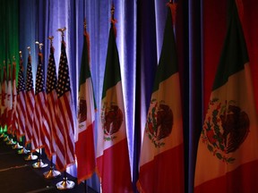 FILE - In this Aug. 16, 2017 file photo, the national flags of Canada, the U.S. and Mexico are lit by stage lights before a news conference, at the start of the North American Free Trade Agreement renegotiations in Washington. Mexico is taking U.S. President Donald Trump's threats to leave NAFTA more seriously as a second round of talks opens Friday, Sept. 1, on renegotiating the 1994 trade pact. Mexico now says it is developing a "Plan B" in case Trump withdraws from the trade pact. (AP Photo/Jacquelyn Martin, File)