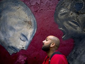 FILE - In this Feb. 9, 2017 file photo, graffiti artist Yulier Rodriguez Perez, artistically known as Yulier P., poses next to one of his works, painted on a wall in Old Havana, Cuba. The Cuban street artist said on Monday, Aug. 21, 2017, that he was detained by police last week and told to erase the 200 or so murals he has painted throughout the country. But the 27-year-old says he has no plans to erase his works. (AP Photo/Ramon Espinosa, File)