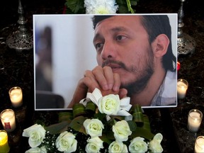 FILE - In this Aug. 3, 2015 file photo, a photograph of murdered photojournalist Ruben Espinosa sits among flowers and candles in front of his casket inside a funeral home before his wake begins in Mexico City. Mexico's surveillance scandal widened Wednesday, August 2 2017, to encompass a pair of prominent human rights attorneys probing a multiple homicide case whose victims include a photojournalist and an activist. The internet watchdog Citizen Lab said Karla Micheel Salas and David Pena were targeted in 2015, weeks after they questioned prosecutors' handling of the killings of activist Nadia Vera, journalist Ruben Espinosa and three other women in a Mexico City apartment in July that year. The victims were tortured and shot to death. (AP Photo/Marco Ugarte, File)