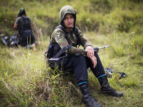 FILE - In this Jan. 6, 2016 file photo, Juliana, a 20-year-old rebel fighter for the 36th Front of the Revolutionary Armed Forces of Colombia, or FARC, rests from a trek in the northwest Andes of Colombia, in Antioquia state. A battle is brewing between Colombia's chief prosecutor and what was recently the nation's largest rebel group over just how much money and property it owns as the former guerrillas transition into becoming a political party. The Revolutionary Armed Forces of Colombia submitted a list of belongings on August 2017, that included farms, cattle and items as miniscule as mops and juice squeezers as required under a peace agreement earlier this month (AP Photo/Rodrigo Abd, File)