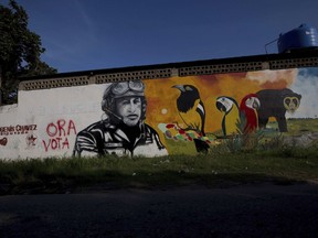 FILE - In this Nov. 23, 2015 file photo, a mural with the image of Venezuela's late President Hugo Chavez shares space with a political ad that urges voters to vote for his cousin, congressional candidate Argenis Chavez, in Barinas, Venezuela. (AP Photo/Fernando Llano, File)