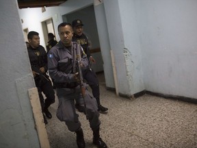 Police go room to room searching for attackers at the Roosevelt Hospital in Guatemala City, Wednesday, Aug. 16, 2017. Officials in Guatemala say at least two people have been killed and five arrested in an early morning shooting at the Roosevelt, one of the country's largest hospitals, where an unknown number of attackers entered the hospital and began shooting. (AP Photo/Luis Soto)