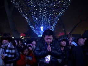 In this Dec. 24, 2015 photo, an overflow crowd prays outside of the Southern Cathedral, an officially-sanctioned Catholic church in Beijing, during a Christmas Eve mass. The Vatican's efforts to heal a decades-long rift with China appear to have stalled, with each side still unwilling to accept controversial bishops appointed by the other. In recent months, Beijing has appeared to take a harder line toward believers, and has ordered the country's estimated 12 million Catholics to shun foreign influence and to "Sinosize" their Church. (AP Photo/Mark Schiefelbein)