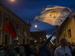 A man waves a Guatemalan flag during a gathering outside the presidential house to show support for the Commissioner of the United Nations International Commission Against Impunity, Ivan Velasquez, who is investigating corruption in Guatemala City, late Thursday, Aug. 24, 2017. Protesters gathered to support the commissioner because they fear Guatemala's President Jimmy Morales will ask for his resignation at the U.N. in New York on Friday. (AP Photo/Moises Castillo)