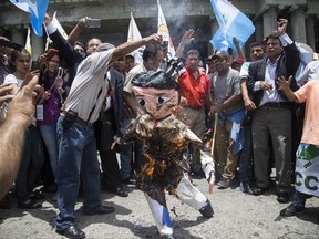 Protesters burn an effigy of Guatemala's President Jimmy Morales during a demonstration in support of Ivan Velasquez, chief of a U.N. anti-corruption commission, in Guatemala City, Monday, Aug. 28, 2017. Guatemalans are coming out to show support for Velasquez, who the president has ordered to leave the country. Last week Attorney General Thelma Aldana and Velasquez called for the removal of the president's immunity from prosecution so they can pursue an investigation into alleged campaign finance violations. (AP Photo/Luis Soto)