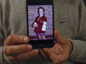 In this July 4, 2017 photo, Rufino Varela shows a portrait of himself on his cell phone when he was 9-years-old, during his first communion ceremony in 1974 at the Cardenal Newman school in Buenos Aires, Argentina. After nearly four decades, Varela broke his silence about sexual abuse he suffered at the hands of Rev. Finnlugh Mac Conastair at the school when he was 12 years old, which has led several other former students to denounce clerical abuse at a school that has educated President Mauricio Macri and many other members of Argentina's elite. (AP Photo/Natacha Pisarenko)