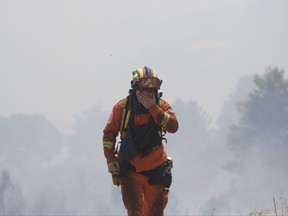 A firefighter puts his hand to his face during a forest fire near Kapandriti north of Athens, Tuesday, Aug. 15, 2017. A large wildfire north of Athens is threatening homes as it sweeps through pine forest for a third day.(AP Photo/Petros Giannakouris)