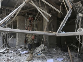 Afghan security guard stands inside a bank after suicide bombing in Kabul, Afghanistan, Tuesday, Aug. 29, 2017.  A suicide bombing on Tuesday in a busy commercial area in Kabul, near a string of banks and not far from the U.S. Embassy, killed several people, Afghan officials said. (AP Photo/Rahmat Gul)