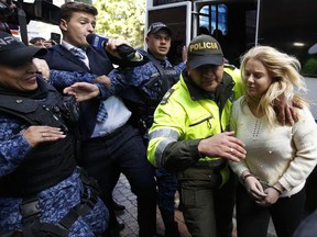 A police officer escorts Australian Cassandra Sainsbury to a court hearing in Bogota, Colombia, Wednesday, Aug. 9, 2017. The 22-year-old was detained April 12 at Bogota's international airport when caught trying to smuggle about 6 kilos of cocaine inside packages of headphones. (AP Photo/Fernando Vergara)