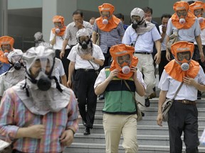 FILE- In this Aug. 18, 2010, file photo, South Koreans wearing gas masks escape from a mock smoke attack during an anti-terror exercise carried out as part of Ulchi Freedom Guardian exercise, against possible attacks from North Korea in Seoul, South Korea. The Ulchi Freedom Guardian drills set to begin Monday, Aug. 21, 2017 will be the first joint military exercise between the allies since North Korea successfully flight-tested two intercontinental ballistic missiles in July and threatened to bracket Guam with intermediate range ballistic missile fire in August. (AP Photo/Lee Jin-man, File)