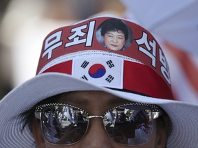 In this Aug. 26, 2017 photo, a photo of former South Korean President Park Geun-hye is seen with letters reading "Innocence, Release" on a supporter's head band during a rally to call for her release in Seoul, South Korea. A small but growing army of often elderly men and women regularly swing South Korean banners and scream outrage at the jailing of a woman they consider their spiritual mother: disgraced former President Park Geun-hye. Pro-Park demonstrations remain tiny relative to earlier protests in which millions demanded her removal from office. Her supporters refuse to accept the possibility that Park may not be the selfless daughter of South Korea she has always portrayed herself to be. (AP Photo/Lee Jin-man)