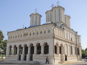A priest walks outside the Romanian Patriarchal Cathedral in Bucharest, Romania, Thursday, Aug. 17, 2017. The Holy Synod of Romania's Orthodox Church is meeting behind closed doors to discuss what action to take against the Bishop of Husi, Corneliu Barladeanu, who was seen on video engaging in sexual acts with a male student, the first time in its 92-year history that the synod gathered to decide on action to take in a sex scandal. (AP Photo/Vadim Ghirda)