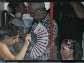 A woman uses a fan to cool herself and a child wile ridding on a tram in Bucharest, Romania, Friday, Aug. 4, 2017. Romanian meteorologists issued an extreme temperatures warning, with 42 Celsius (107.6 F) forecast for parts of western Romania and placing 12 counties under a "red code" heat alert for the next two days. (AP Photo/Vadim Ghirda)