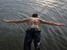 A man jumps in a lake in Silistea Snagovului, Romania, Sunday, Aug. 6, 2017. A heatwave with temperatures of up to 42 Celsius (107.6 F) affected Romania over the past week and is expected to continue for the coming days in some parts of the country. (AP Photo/Vadim Ghirda)