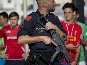 An armed policeman grimaces while on patrol in Cambrils, Spain, Friday, Aug. 18, 2017. Spanish police on Friday shot and killed five people carrying bomb belts who were connected to the Barcelona van attack that killed at least 13, as the manhunt intensified for the perpetrators of Europe's latest rampage claimed by the Islamic State group. (AP Photo/Emilio Morenatti)