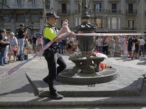 A police officer removes a no access police tape in Las Ramblas, Barcelona, Spain, Friday, Aug. 18, 2017.
