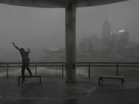 People play with strong wind caused by Typhoon Hato on the waterfront of Victoria Habour in Hong Kong, Wednesday, Aug. 23, 2017. The powerful typhoon barreled into Hong Kong on Wednesday, forcing offices and schools to close and leaving flooded streets, shattered windows and hundreds of canceled flights in its wake. (AP Photo/Vincent Yu)