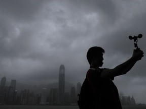 A man raises an anemometer against the strong wind caused by tropical storm Pakhar on the waterfront of Victoria Habour in Hong Kong, Sunday, Aug. 27, 2017. The Hong Kong Observatory says Severe Tropical Storm Pakhar has made landfall over Taishan of Guangdong. (AP Photo/Vincent Yu)