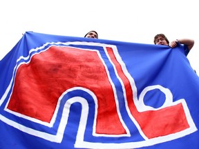 In this April 10, 2011 file photo, two fans hold the official flag of the Nordiques Nation, a group of hockey fans campaigning for the transfer of any money-losing American NHL franchise to Quebec City.