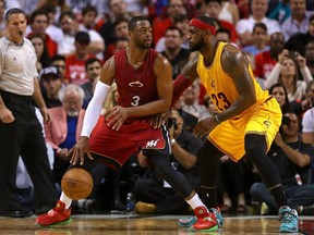 In this Dec. 25, 2014 file photo, Miami Heat guard Dwyane Wade (left) backs down Cleveland Cavaliers forward LeBron James, his former teammate.