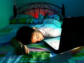 A child sleeps in front of a laptop.