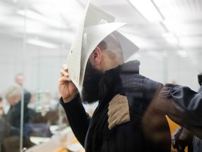 Abu Walaa hides his face as he arrives at court for the opening of his trial on September 26, 2017 in Celle near Hanover, central Germany