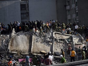 Rescuers, firefighters, policemen, soldiers and volunteers remove rubble and debris from a flattened building in search of survivors after a powerful quake in Mexico City on September 19, 2017