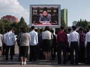 Spectators listen to a television news brodcast of a statment by North Korean leader Kim Jong-Un, before a public television screen outside the central railway station in Pyongyang on September 22, 2017.