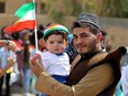 An Iraqi Kurdish man poses as he carries a child wearing the Kurdish flag on his head during a celebration in the northern city of Kirkuk on September 25, 2017 as Iraqi Kurds vote in a referendum on independence. The non-binding vote, initiated by veteran Kurdish leader Massud Barzani, has angered not only Baghdad, following which Iraq's federal parliament demanded that troops be sent to disputed areas in the north controlled by the Kurds since 2003, but also neighbours Turkey and Iran who are concerned it could stoke separatist aspirations among their own sizeable Kurdish minorities.