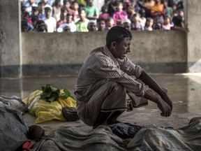 A Rohingya Muslim refugee mourns beside the bodies of his three children at a school near Inani beach in Cox's Bazar district on September 29, 2017