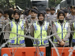 Police officers stand guard behind a razor wire barricade during a rally outside the Myanmar's Embassy in Jakarta, Indonesia, Wednesday, Sept. 6, 2017. Indonesian Muslims staged the angry protest against Myanmar's persecution of its Rohingya Muslim minority and calling for the government to take a tougher stance against it. (AP Photo/Achmad Ibrahim)