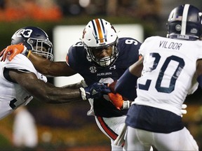 In this Saturday, Sept. 2, 2017, photo, Auburn running back Kam Martin, center, runs the ball in the second half against Georgia Southern linebacker Tomarcio Reese of an NCAA college football game in Auburn, Ala. Martin couldn't sleep much during a trying week. The Auburn tailback's family was stuck at their house in Port Arthur, Texas, and his aunt passed away amid flooding. Martin's parents saw the third-team tailback have a career game with 136 yards against Georgia Southern. (AP Photo/Brynn Anderson)