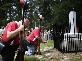 FILE- In this Aug. 27, 2017 file photo members of the Sons of Confederate Veterans kneel in front of a new monument called the "Unknown Alabama Confederate Soldiers" in the Confederate Veterans Memorial Park in Brantley, Ala. As Confederate statues across the nation get removed, covered up or vandalized, some brand new ones are being built as well. (AP Photo/Brynn Anderson, File)