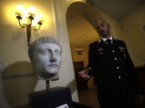 Italian Carabinieri officer Massimo Maresca shows the first century A.C. Druso marble head during an interview in the Carabinieri barracks, Friday, Sept. 1, 2017. The Cleveland Museum of Art gave it back to Italy after learning the piece depicting Emperor Tiberius' son had been stolen, apparently by Algerian troops, from southern Italy toward the end of World War II, brought into France, eventually sold at auction in Paris and acquired by the museum in 2012. (AP Photo/Alessandra Tarantino)