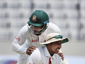 Bangladesh's Imrul Kayes congratulates his teammate Soumya Sarkar, on ground, for taking a catch to successfully dismiss Australia's Peter Handscomb, unseen, during the fourth day of their first test cricket match in Dhaka, Bangladesh, Wednesday, Aug. 30, 2017. (AP Photo/A.M. Ahad)