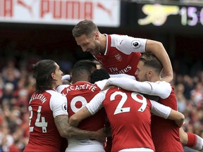 Arsenal's Danny Welbeck is surrounded by teammates as they celebrate him scoring his side's first goal of the game, during the English Premier League soccer match between Arsenal and Bournemouth, at the Emirates Stadium, in London, Saturday Sept. 9, 2017. (John Walton/PA via AP)