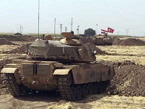 Turkish and Iraqi soldiers sit on Turkish tanks during the exercises in Silopi, near the Habur border gate with Iraq, southeastern Turkey, Tuesday, Sept. 26, 2017. Tanks with soldiers holding the Turkish and Iraqi flags rolled on a field lifting up dust, as the two countries' militaries conducted joint exercises on Turkey's border with Iraq's semi-autonomous Kurdish region.(AP Photo/Mehmet Guzel )