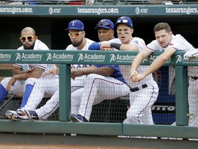 Texas Rangers' Rougned Odor, from left, Robinson Chirinos, Adrian Beltre, Drew Robinson and Phil Gosselin watch play against the Houston Astros from the top of the dugout in the ninth inning of a baseball game, Wednesday, Sept. 27, 2017, in Arlington, Texas. The Astros won 12-2. (AP Photo/Tony Gutierrez)