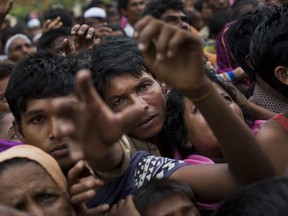 In this Sunday, Sept. 3, 2017, file photo, Myanmar's Rohingya ethnic minority refugees reach for food distributed by Bangladeshi volunteers near Cox's Bazar's Gundum area, Bangladesh. Aid officials said relief camps were reaching full capacity as thousands of Rohingya refugees continued to pour into Bangladesh on Sunday fleeing violence in western Myanmar. Some 73,000 people have crossed the border since violence erupted Aug. 25 in Myanmar's Rakhine state, said U.N. High Commissioner for Refugees spokeswoman Vivian Tan. (AP Photo/Bernat Armangue, File)