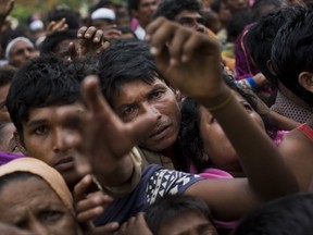 Myanmar's Rohingya ethnic minority refugees reach for food distributed by Bangladeshi volunteers near Cox's Bazar's Gundum area, Bangladesh, Sunday, Sept. 3, 2017. Aid officials said relief camps were reaching full capacity as thousands of Rohingya refugees continued to pour into Bangladesh on Sunday fleeing violence in western Myanmar. Some 73,000 people have crossed the border since violence erupted Aug. 25 in Myanmar's Rakhine state, said U.N. High Commissioner for Refugees spokeswoman Vivian Tan. (AP Photo/Bernat Armangue)