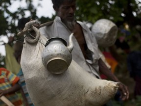 In this Thursday, Sept. 7, 2017, photo, a Rohingya Muslim man arrives with a sack of belongings and a kettle tied to a stick as he crosses the border into Bangladesh's Teknaf area. Group upon group of terrified, starving, exhausted Rohingya Muslims arrive in Bangladesh carrying with them precious items packed into used sacks and bamboo baskets as they flee on foot through forests or on precarious boats on rain-swollen rivers to escape the most recent violence to engulf their homeland since Aug. 25. when a group of Rohingya insurgents attacked a series of police post in Myanmar. (AP Photo/Bernat Armangue)