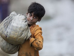 In this Wednesday, Sept. 20, 2017 photo, a Rohingya Muslim boy walks carrying belongings near Balukhali refugee camp in Cox's Bazar, Bangladesh. Children make up about 60 percent of the sea of humanity that has poured in to Bangladesh over the last four weeks fleeing terrible persecution in Myanmar. And the U.N.'s child rights agency UNICEF has so far counted about 1,400 children who have crossed the border without their parents. (AP Photo/Bernat Armangue)